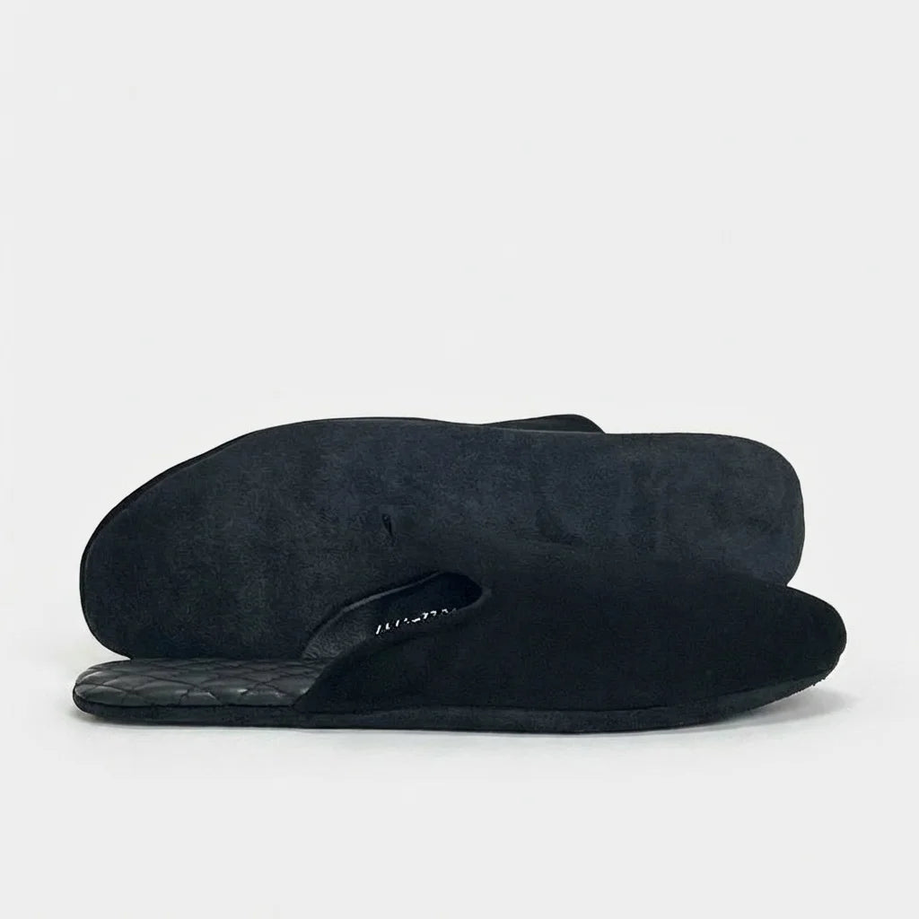 Men's black leather mule slippers, one on its side showing the sole